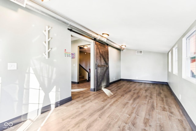 unfurnished room featuring a barn door and light hardwood / wood-style floors