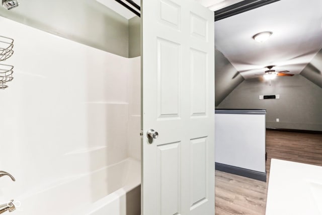 bathroom featuring hardwood / wood-style floors, ceiling fan, bathing tub / shower combination, and vaulted ceiling