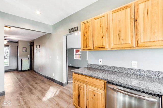 kitchen with light brown cabinets, stainless steel dishwasher, ceiling fan, dark stone countertops, and light wood-type flooring