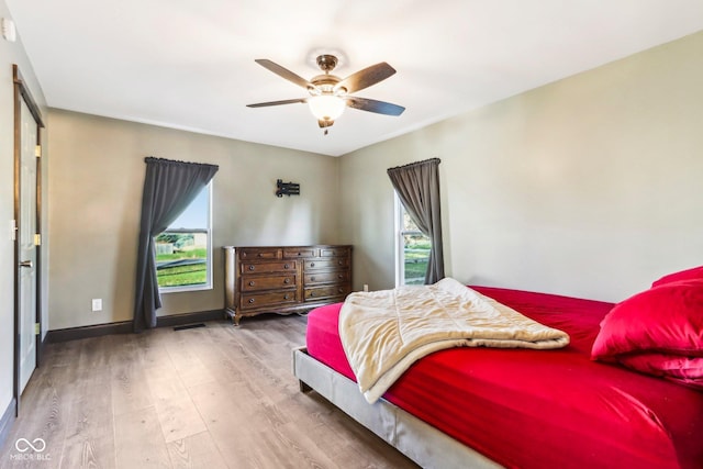 bedroom with hardwood / wood-style flooring, ceiling fan, and multiple windows