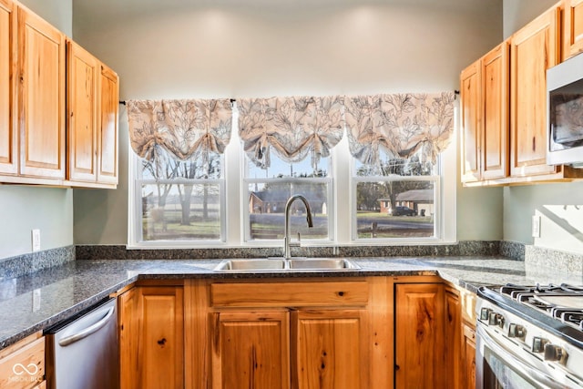 kitchen featuring sink, dark stone counters, and stainless steel appliances