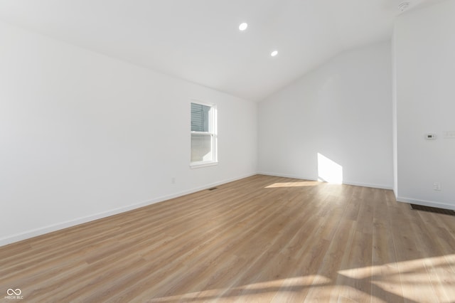 spare room with lofted ceiling and light wood-type flooring