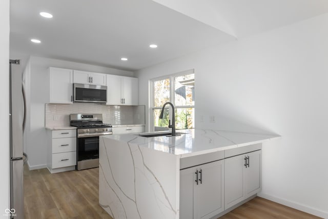 kitchen with white cabinets, light hardwood / wood-style floors, sink, and appliances with stainless steel finishes