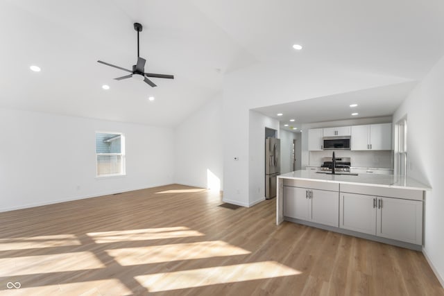 kitchen featuring sink, tasteful backsplash, light hardwood / wood-style flooring, white cabinets, and appliances with stainless steel finishes