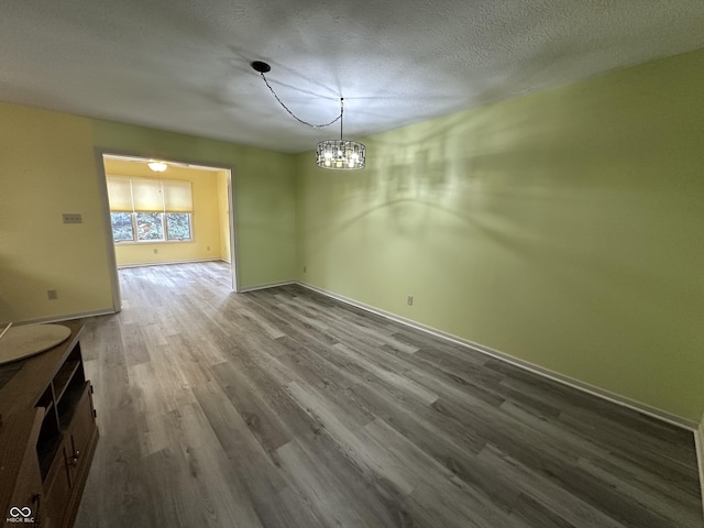 unfurnished dining area featuring a textured ceiling, hardwood / wood-style flooring, and an inviting chandelier