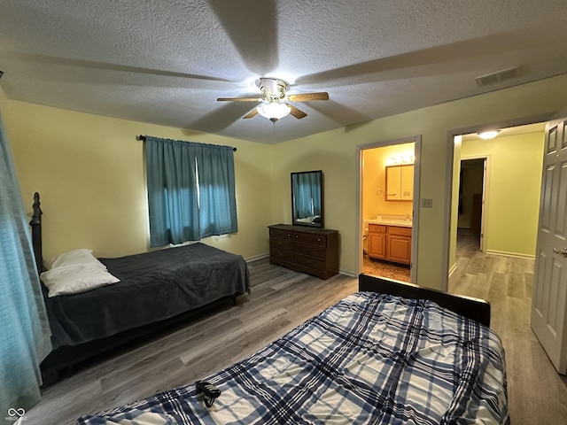 bedroom with ensuite bath, ceiling fan, hardwood / wood-style floors, and a textured ceiling