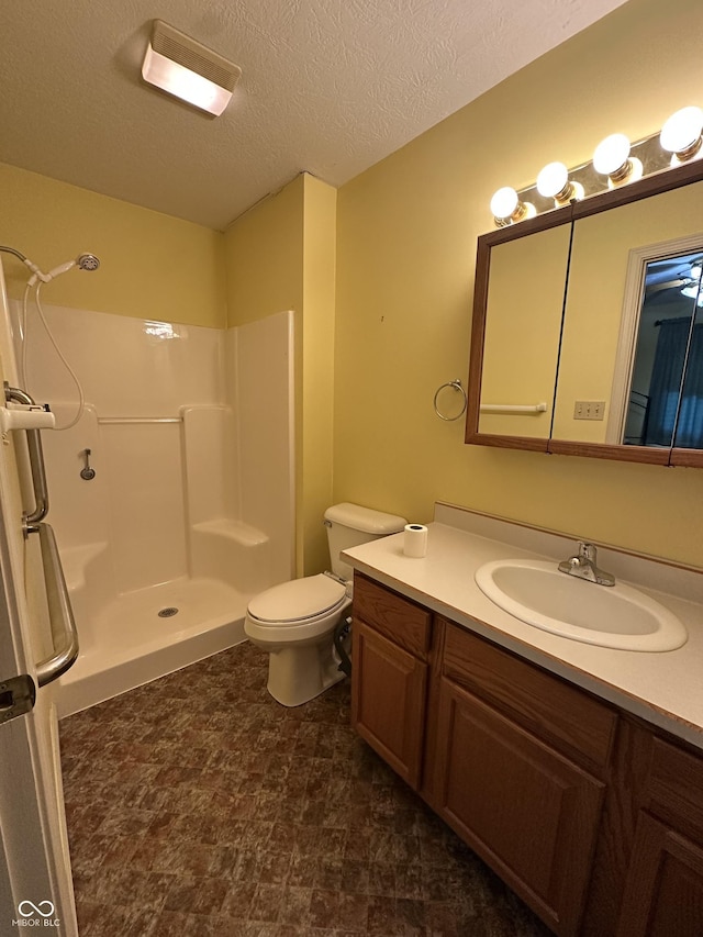 bathroom with vanity, toilet, a textured ceiling, and walk in shower