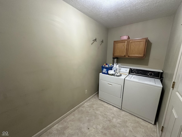 laundry area featuring cabinets, a textured ceiling, washing machine and dryer, and light carpet