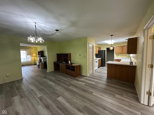 kitchen with sink, wood-type flooring, kitchen peninsula, and an inviting chandelier