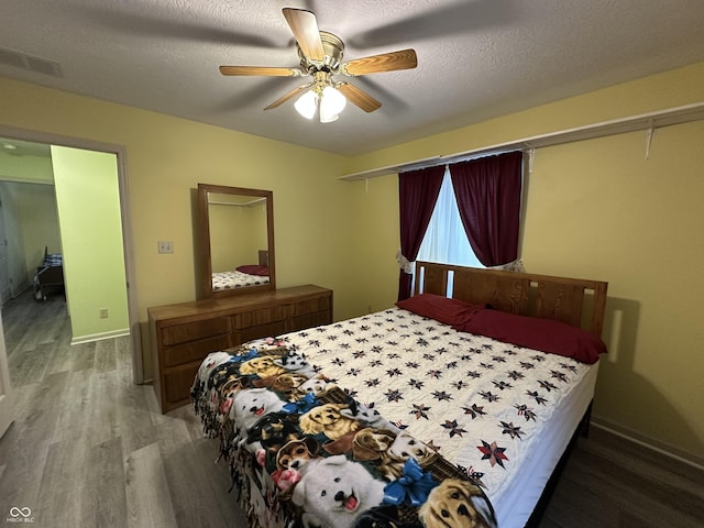 bedroom featuring hardwood / wood-style floors, a textured ceiling, and ceiling fan