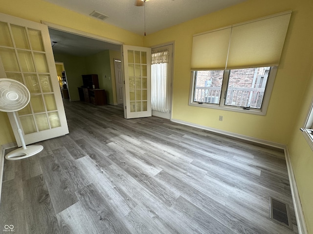 unfurnished dining area featuring french doors, a textured ceiling, and hardwood / wood-style flooring