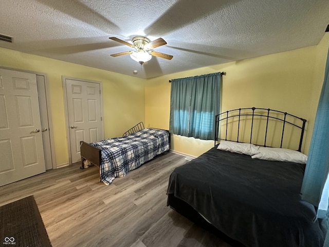 bedroom featuring ceiling fan, wood-type flooring, and a textured ceiling