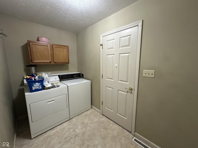 clothes washing area featuring separate washer and dryer, light colored carpet, cabinets, and a textured ceiling