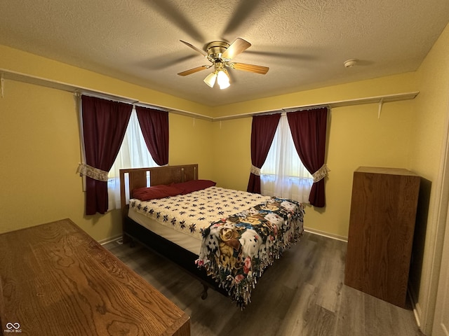 bedroom featuring multiple windows, a textured ceiling, dark hardwood / wood-style flooring, and ceiling fan