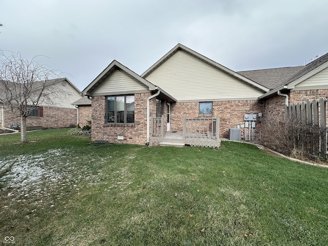 rear view of house with central AC, a deck, and a lawn