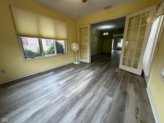 unfurnished room featuring a chandelier, french doors, and hardwood / wood-style flooring