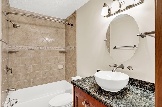 full bathroom with vanity, toilet, a textured ceiling, and tiled shower / bath combo