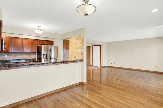 kitchen with sink, stainless steel appliances, tasteful backsplash, dark stone countertops, and light wood-type flooring