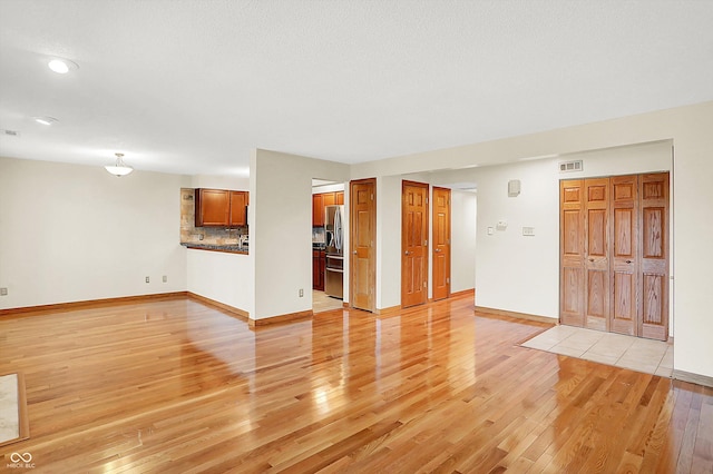 unfurnished living room with a textured ceiling and light wood-type flooring