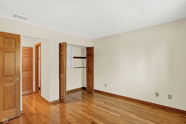 unfurnished bedroom with a textured ceiling and light hardwood / wood-style flooring