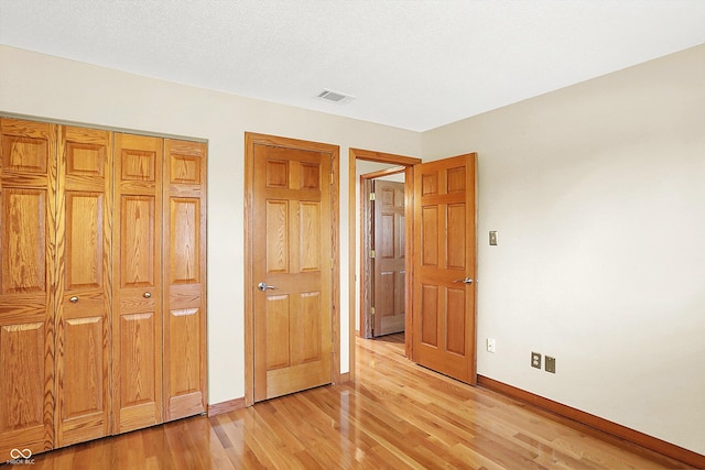 unfurnished bedroom featuring a closet, light hardwood / wood-style flooring, and a textured ceiling