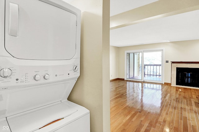 laundry room featuring light hardwood / wood-style floors and stacked washer and clothes dryer