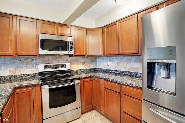 kitchen with backsplash, dark stone counters, light tile patterned floors, a textured ceiling, and stainless steel appliances