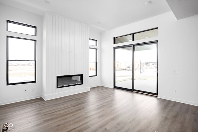 unfurnished living room featuring a fireplace, a wealth of natural light, and dark wood-type flooring