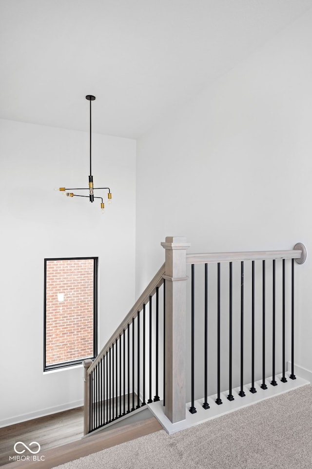 staircase featuring wood-type flooring and a notable chandelier