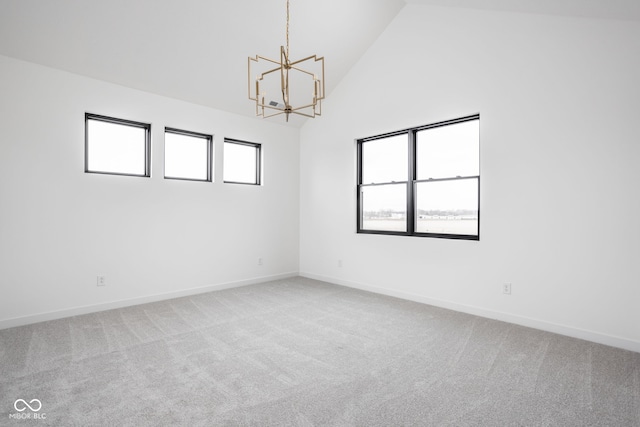 carpeted spare room featuring an inviting chandelier and high vaulted ceiling