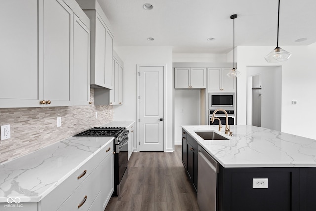 kitchen with sink, hanging light fixtures, stainless steel appliances, an island with sink, and white cabinets