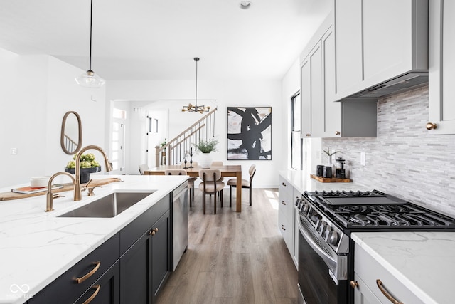 17366 Newton Main St, Westfield, IN 46074 - kitchen with appliances with stainless steel finishes, a sink, light wood finished floors, tasteful backsplash, and a chandelier