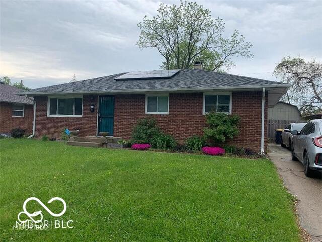 single story home featuring a front yard and solar panels