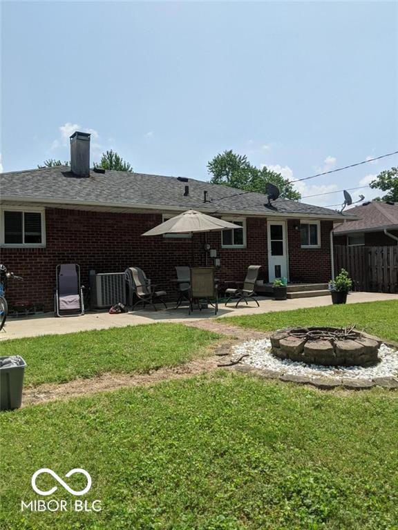 rear view of house featuring a yard, a patio, and an outdoor fire pit