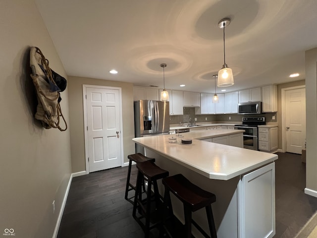 kitchen with appliances with stainless steel finishes, sink, decorative light fixtures, white cabinets, and a kitchen island