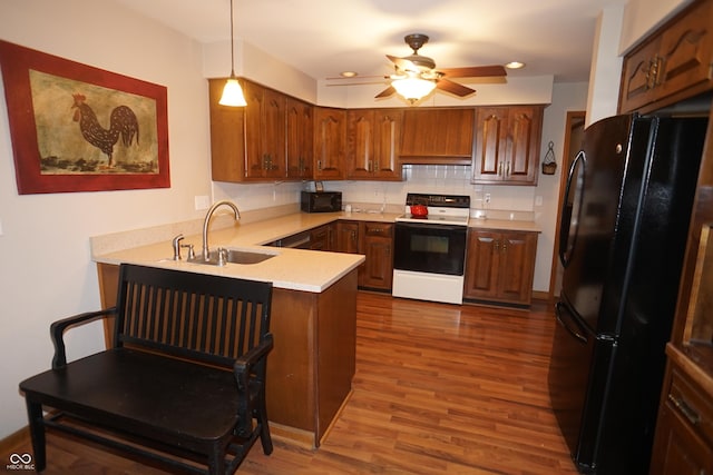 kitchen featuring sink, hanging light fixtures, dark hardwood / wood-style floors, kitchen peninsula, and black appliances