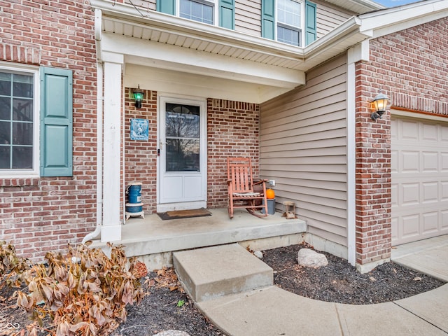 view of exterior entry featuring a porch and a garage