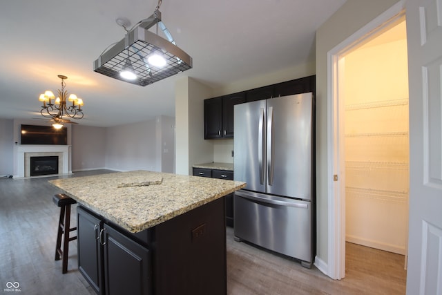 kitchen featuring light wood-type flooring, stainless steel refrigerator, a kitchen breakfast bar, a kitchen island, and pendant lighting