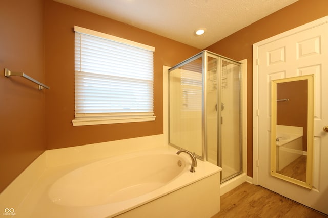 bathroom featuring plus walk in shower, hardwood / wood-style floors, and a textured ceiling