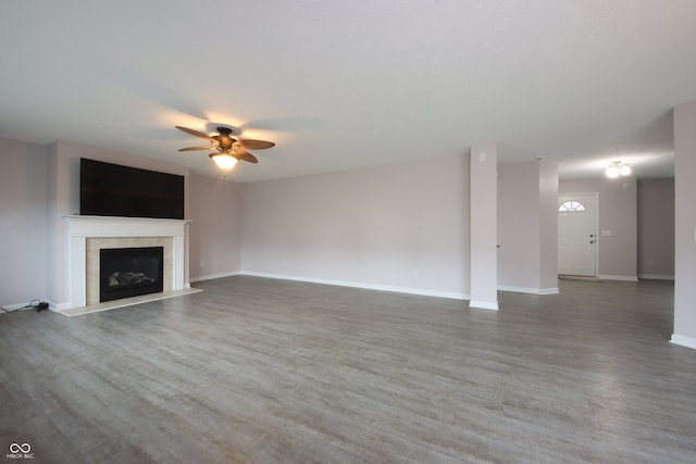 unfurnished living room featuring a tiled fireplace, wood-type flooring, and ceiling fan