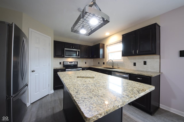 kitchen with light stone countertops, appliances with stainless steel finishes, a center island, and sink