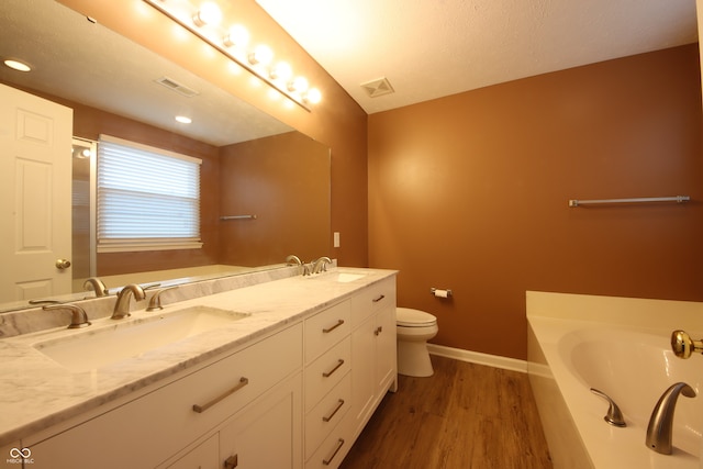 bathroom featuring a washtub, hardwood / wood-style floors, vanity, and toilet