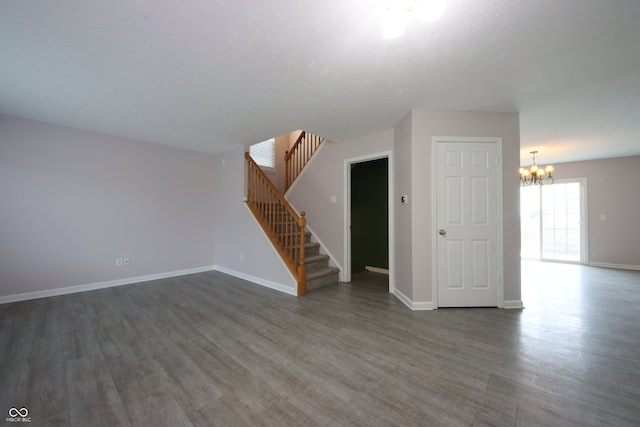 empty room with a notable chandelier and dark hardwood / wood-style floors