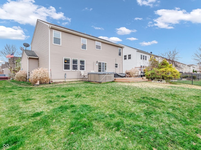 rear view of property featuring a wooden deck and a lawn