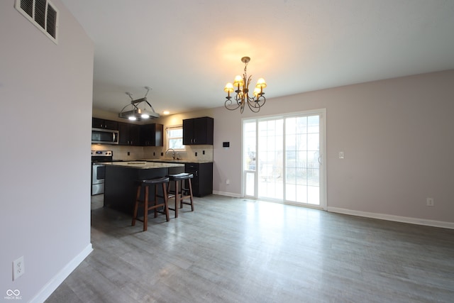 kitchen with sink, an inviting chandelier, appliances with stainless steel finishes, a kitchen breakfast bar, and backsplash