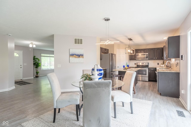 14446 Chapelwood Ln, Fishers, IN 46037 - dining area featuring a notable chandelier, baseboards, visible vents, and light wood-style floors