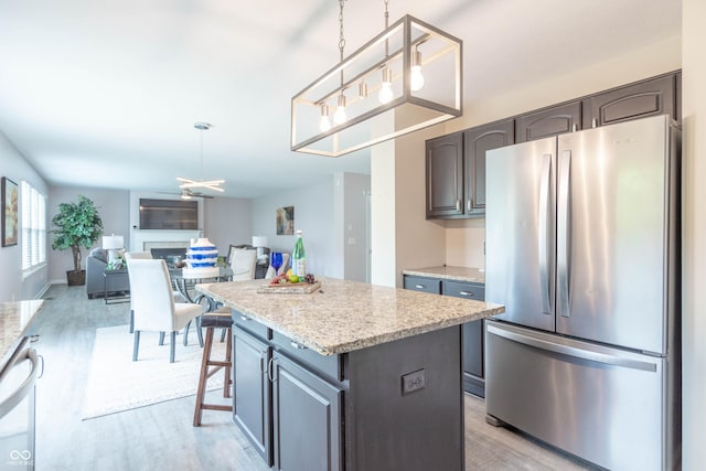 14446 Chapelwood Ln, Fishers, IN 46037 - kitchen with freestanding refrigerator, hanging light fixtures, a center island, and light wood-style floors