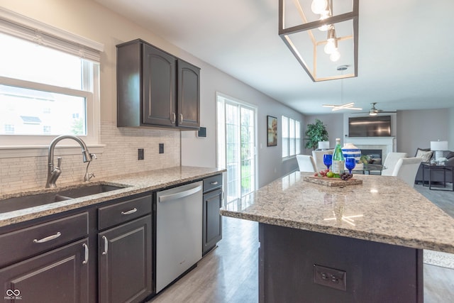 14446 Chapelwood Ln, Fishers, IN 46037 - kitchen featuring decorative backsplash, a center island, stainless steel dishwasher, a sink, and a glass covered fireplace