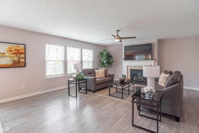 14446 Chapelwood Ln, Fishers, IN 46037 - living room with a fireplace, a textured ceiling, a ceiling fan, baseboards, and wood finished floors