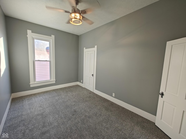 unfurnished room with dark colored carpet, ceiling fan, and a textured ceiling